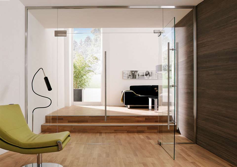 Frameless double swing glass doors with stainless steel top and bottom patch fittings and vertical pull handles on each door leaf.